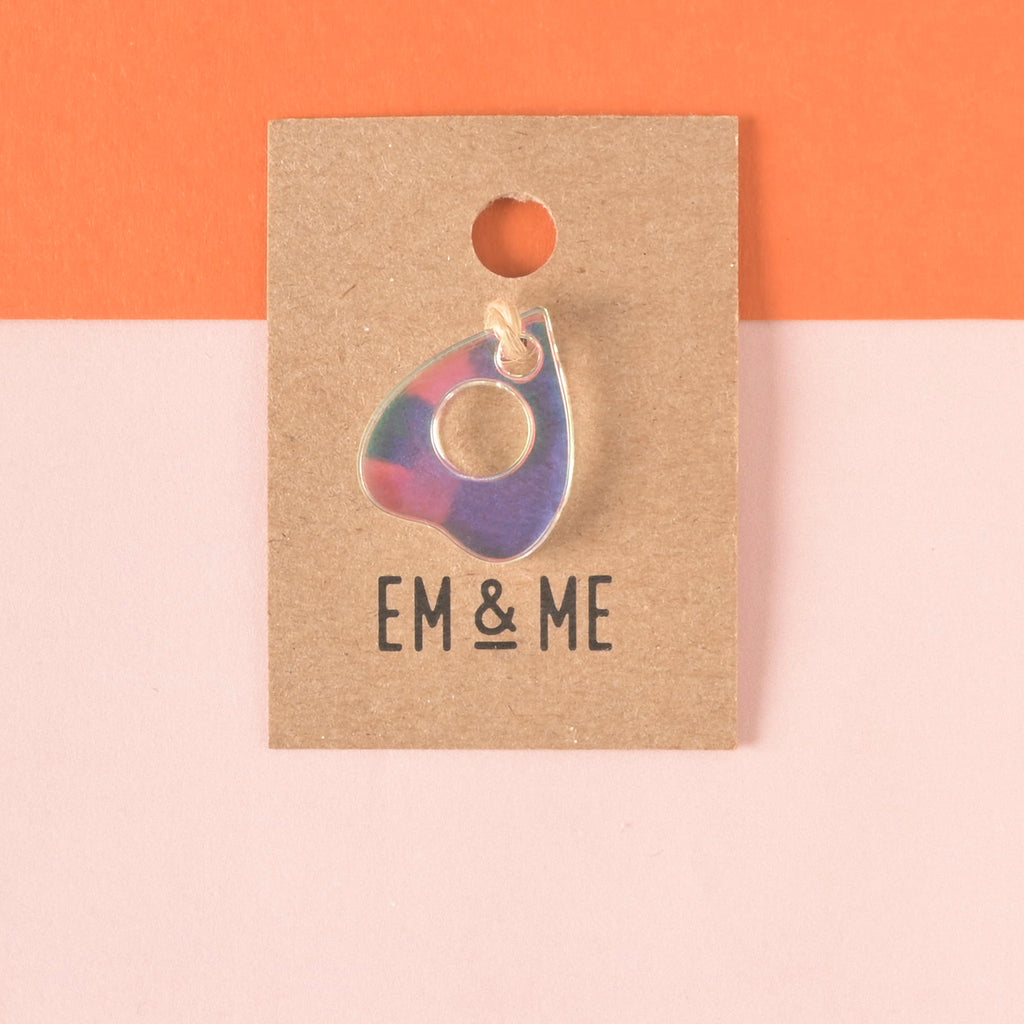 iridescent acrylic ouija planchet-shaped ini charm add on packaged on brown kraft paper.