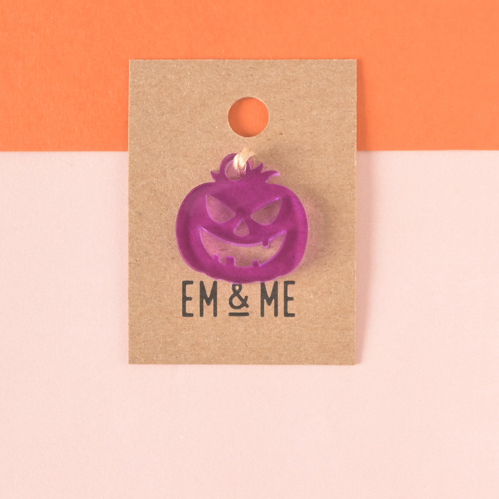 purple jack-o-lantern shaped seasonal mini charm packaged on brown kraft paper on color blocked background