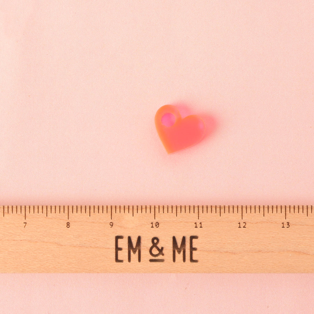 Fluorescent pink tiny heart charm with a ruler that reads EM & ME" on a solid pink background