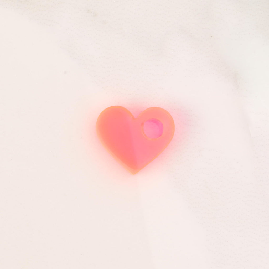 fluorescent pink tiny heart charm on solid white background