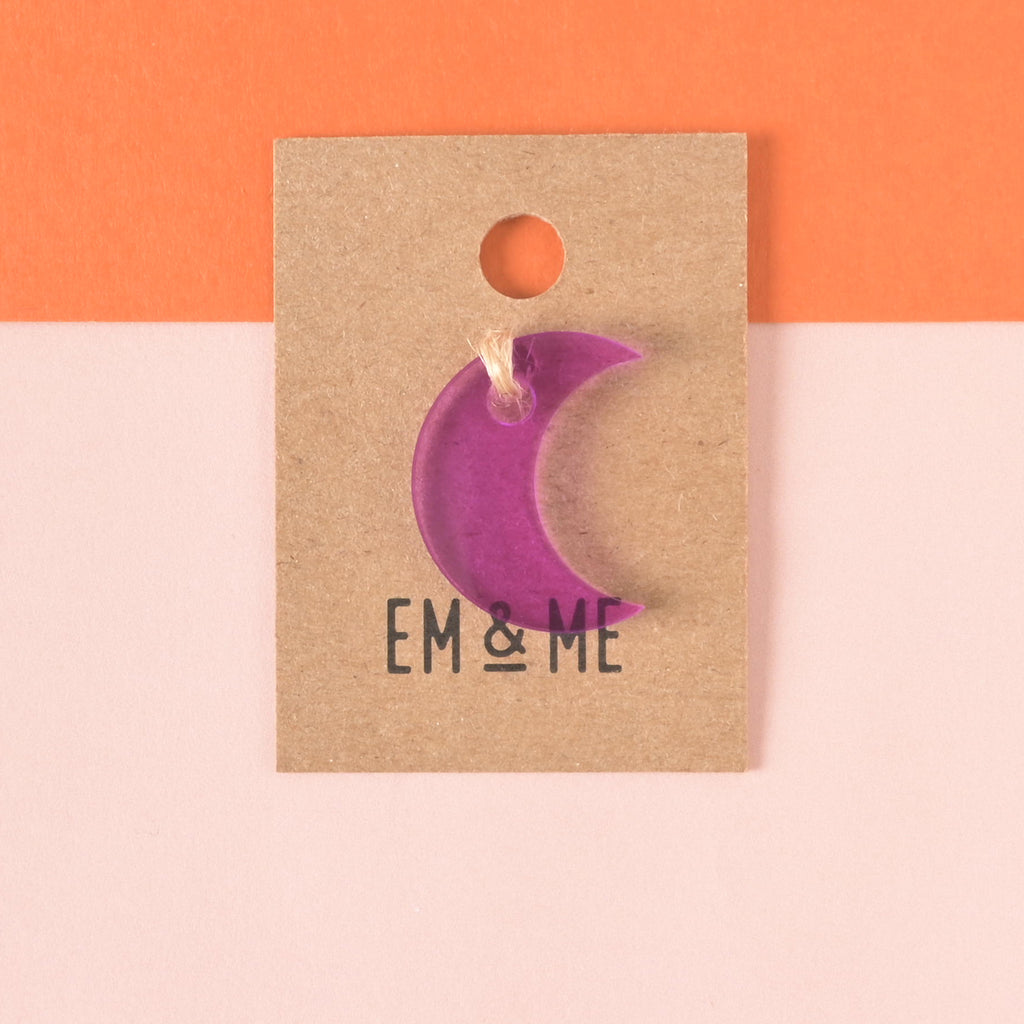 purple moon-shaped seasonal mini charm packaged on brown kraft paper on color blocked backgrund.