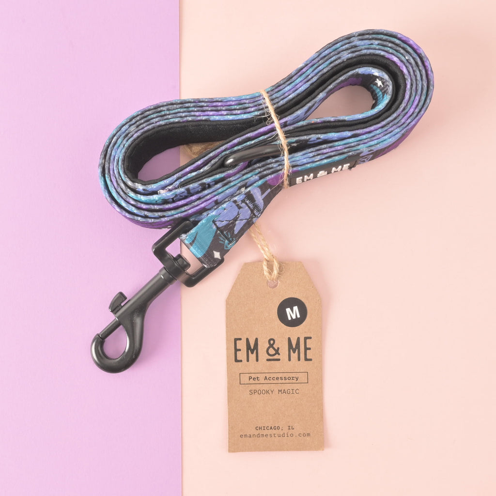 Rolled EM & ME spooky magic pet leash with product tag and branding displayed on a pink and purple background.