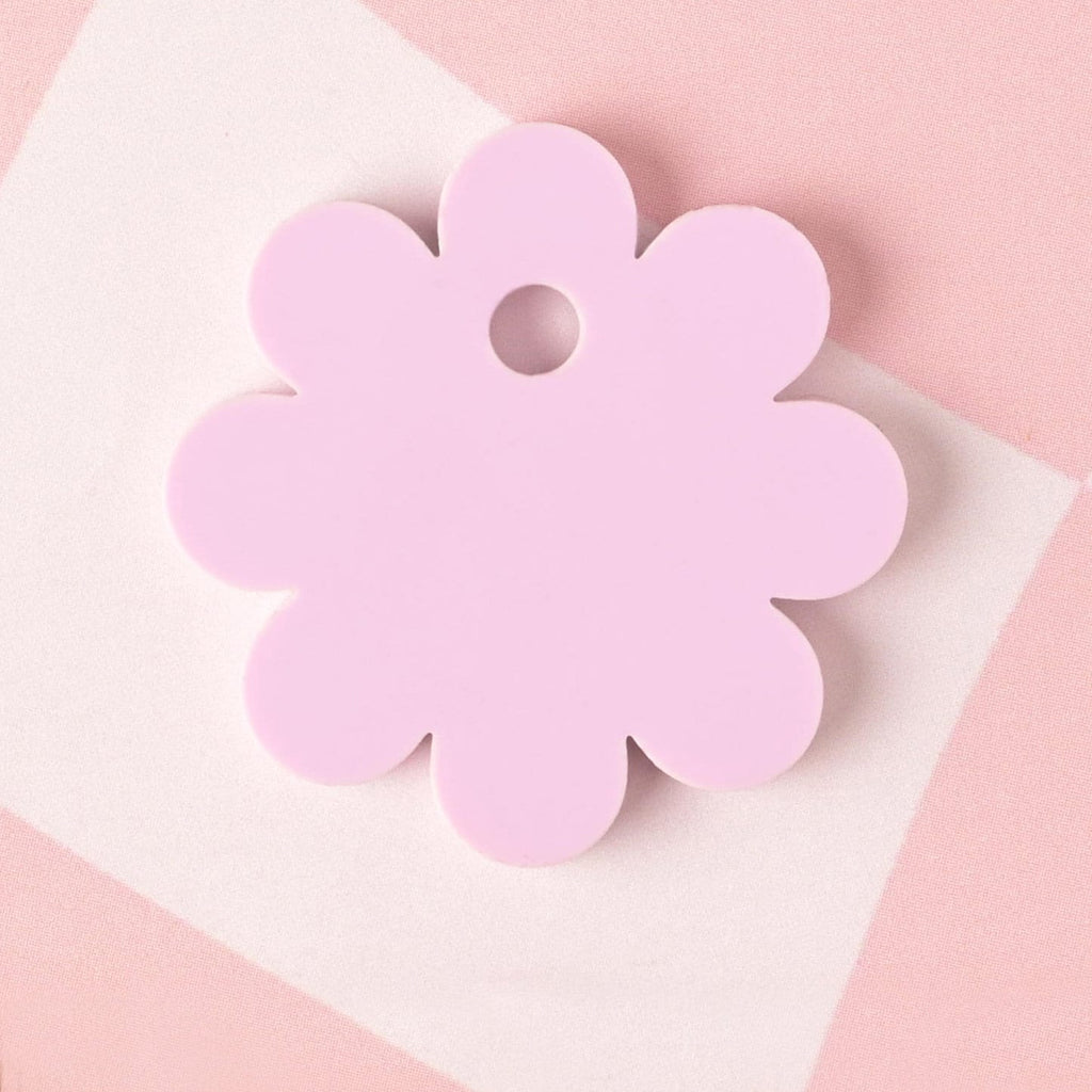 Back side of a lavender acrylic daisy-shaped pet ID tag with no engraving, placed on a pink checkered background