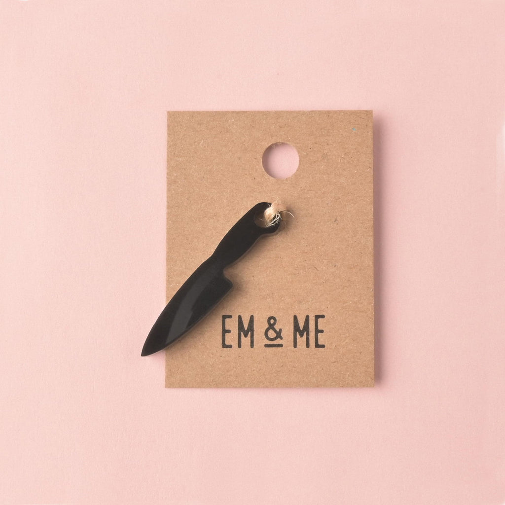 fake knife, Seasonal Mini,  Tiny Accessory for Pet ID Tag, Cats and Dogs Add-on Charm A small, opaque black acrylic mini charm shaped like a chef's knife, secured to a brown kraft jewelry card branded with 'EM & ME.'