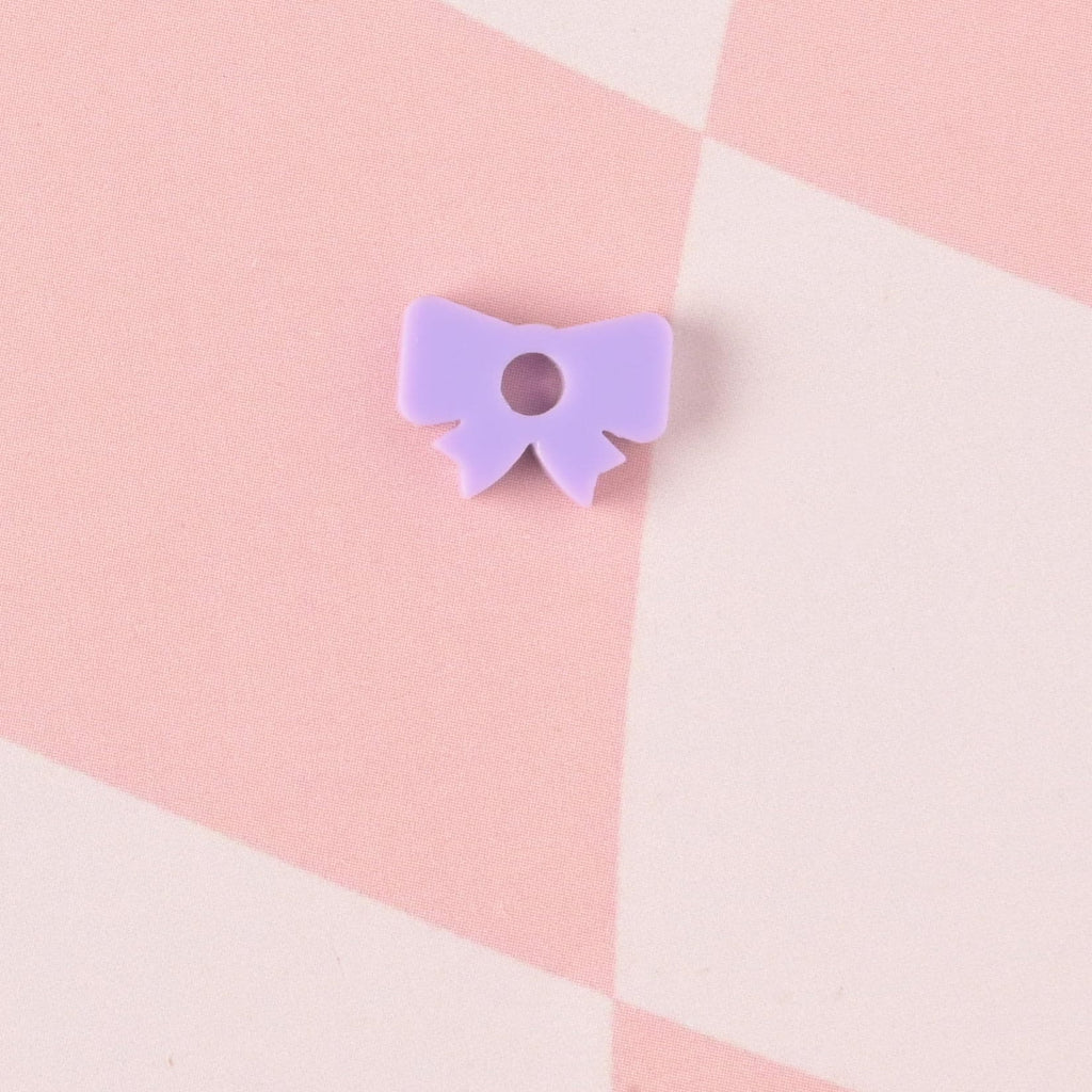 close-up of a lavender Bow, Seasonal Mini, Tiny bow Accessory for Pet ID Tag, Cats and Dogs Add-on Charm on checked pink background