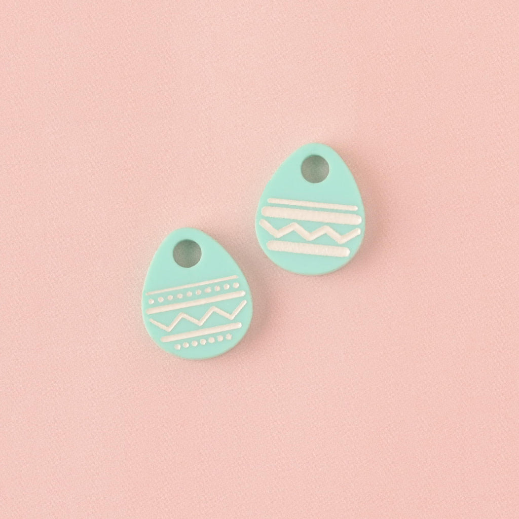 Two mint green Easter egg pet charms. Pastel acrylic mini tags with white engraved patterns. Spring pet accessories.