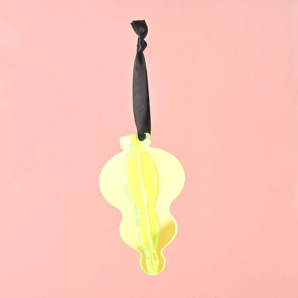 A single 3D interlocking acrylic Christmas ornament in a stylized, contoured bulb shape. It is constructed from bright fluorescent green acrylic pieces, hanging from a black ribbon against a solid pink background.Acrylic Icicle Christmas ornaments, bright colors and non-breakable, contemporary 70s inspired Holiday