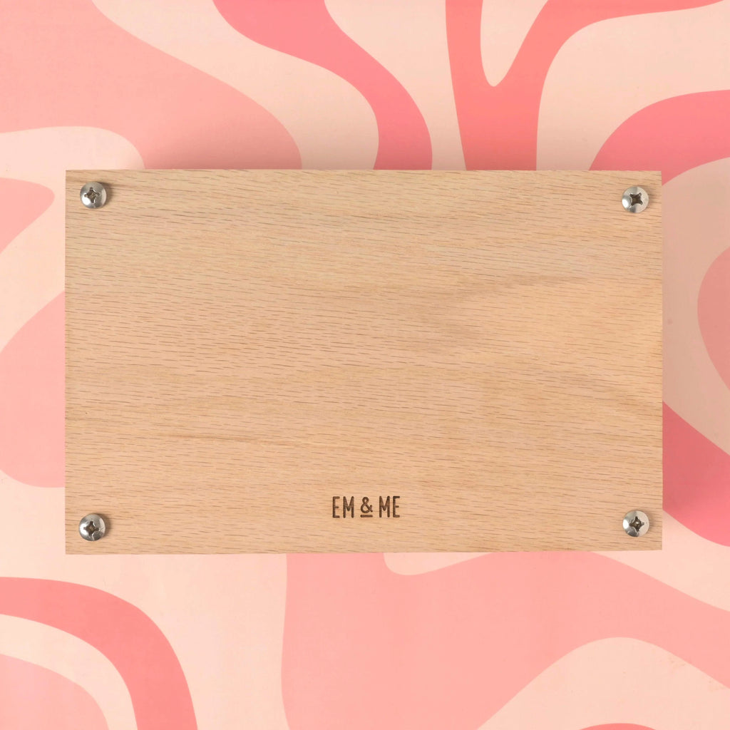 Back panel of oak flower press kit engraved with Em & Me Studio logo on pink patterned background