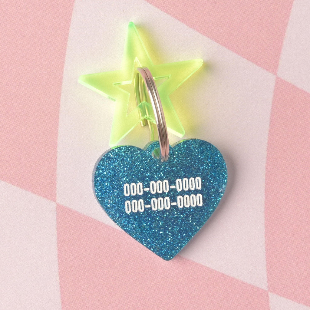 A custom heart-shaped pet ID tag made from vibrant blue glitter acrylic. The tag is engraved with two lines of phone numbers and accented with a large fluorescent neon yellow-green star charm on a split ring. Barbie Inspired Personalized Pet Tag, Taffy Heart Shaped Tag for Cats and Dogs, Limited Edition, Custom Name and Contact Info Engraved