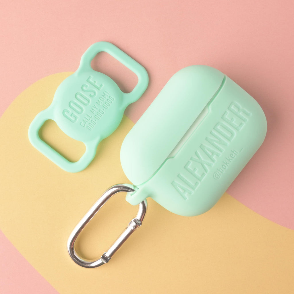 A matching set of mint green silicone accessories: a personalized AirPods Pro case engraved with 'ALEXANDER' and a social handle, and a silicone dog tag engraved with the name 'GOOSE' and contact information.