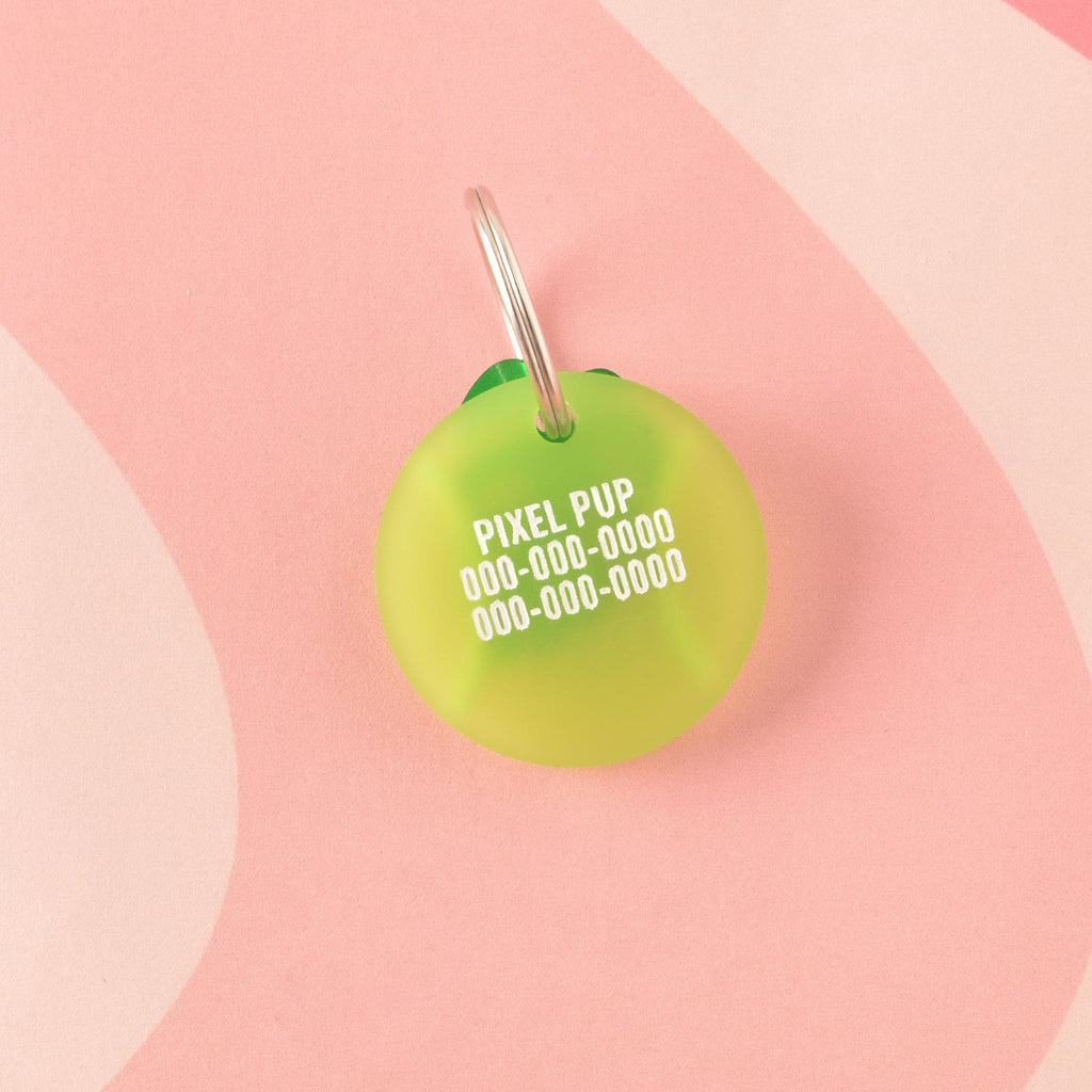 A custom circular pet ID tag shaped like a tennis ball in frosted lime green acrylic. The tag is engraved with the name 'PIXEL PUP' and three lines of phone numbers in white. Tennis Ball Pet Tag, Personalized Pet tag, Cat or Dog ID Tag, summer ball tag