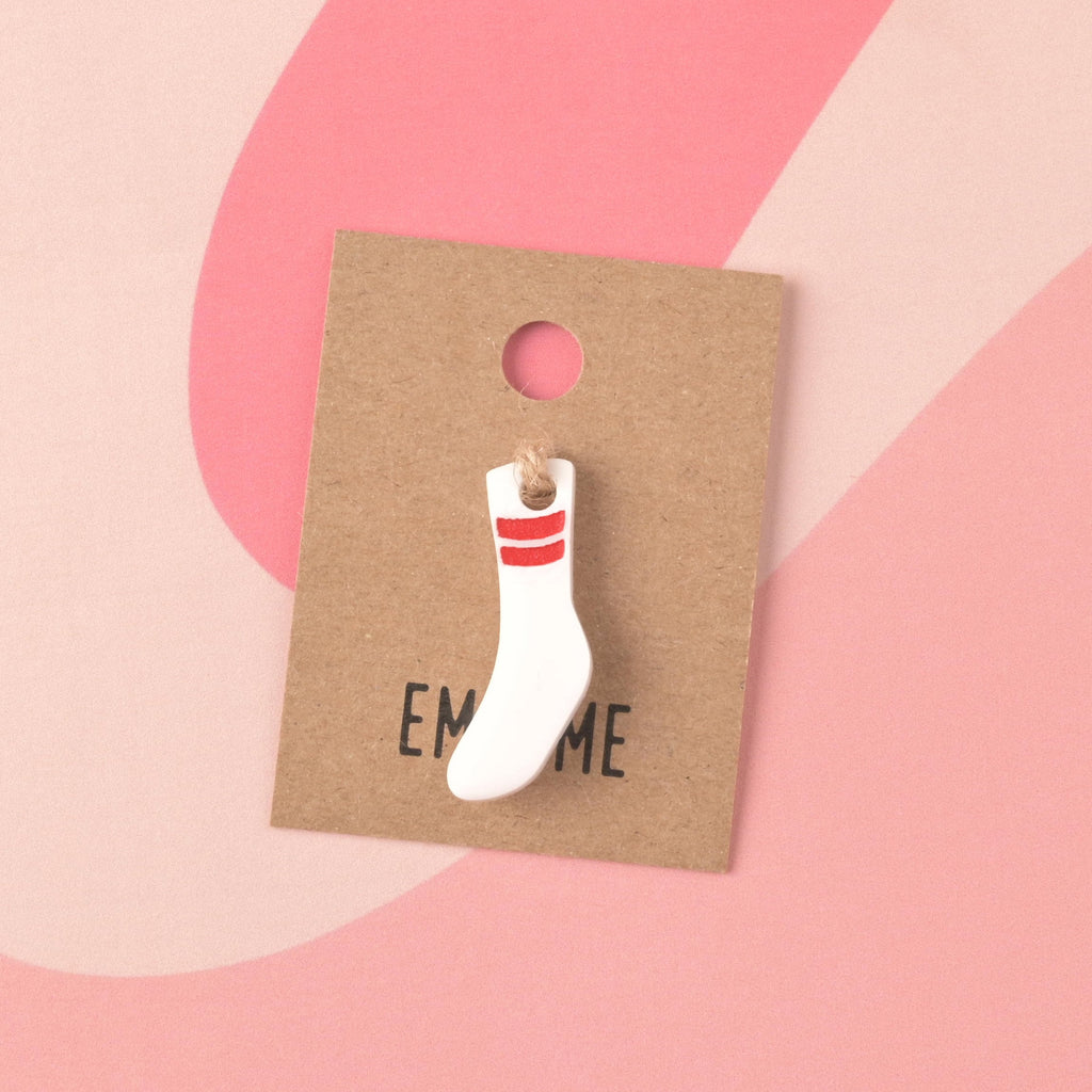 A small, opaque white acrylic mini charm shaped like a tube sock with red stripes, secured to a brown kraft jewelry card branded with 'EM & ME.' Tubesock, Missing Sock, Seasonal Mini, Tiny Accessory for Pet ID Tag, Cats and Dogs Add-on Charm