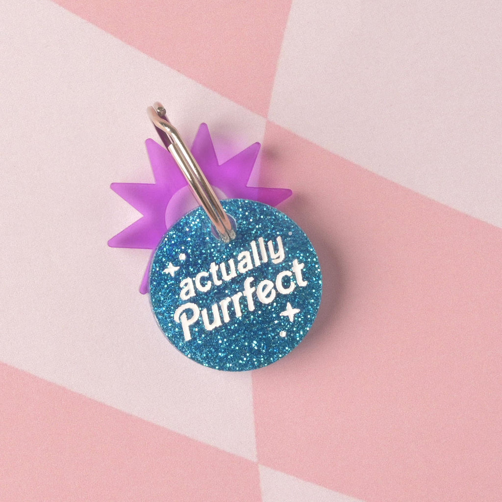  A round acrylic tag made from vibrant blue glitter, engraved with the white slogan "actually Purrfect". The tag is accented with a translucent purple sunburst charm and a silver split ring. Personalized Barbie-Inspired Cat Tag, Custom Engraved with Contact Info, Limited Edition "Actually Purrfect" Design, Dollhouse for kittens